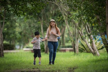 Anne ve oğlunun portresi parkta el ele yürürken mutludur. Aile kavramı.