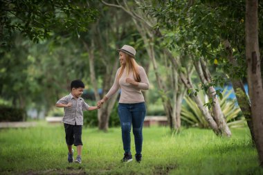 Anne ve oğlunun portresi parkta el ele yürürken mutludur. Aile kavramı.
