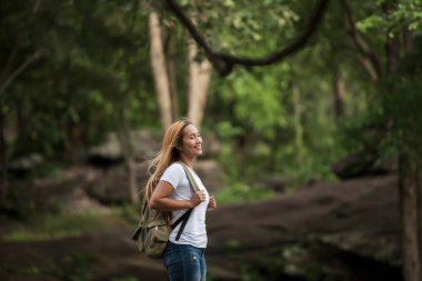 Sırt çantalı genç turist kadın dağın tepesinde durarak doğanın tadını çıkarıyor..