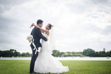 Düğünde gülümseyen mutlu bir çift. Güzel gelin ve yakışıklı damat doğada muhteşem bir mevki.