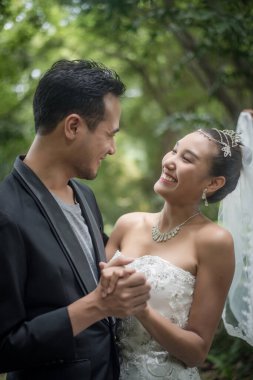 Gelin ve damat arka planda yeşil parkla duruyorlar..