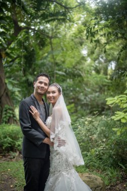 Gelin ve damat arka planda yeşil parkla duruyorlar..