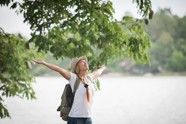 Sırt Çantalı Genç Mutlu Bir Kadın Ellerini Kaldırmış Nehre Bakıyor — Stok fotoğraf