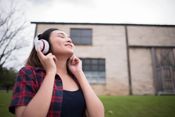 Close up of young hipster woman listening to music with mobile phone outdoor. Happy smiling girl listening to music with earphone.