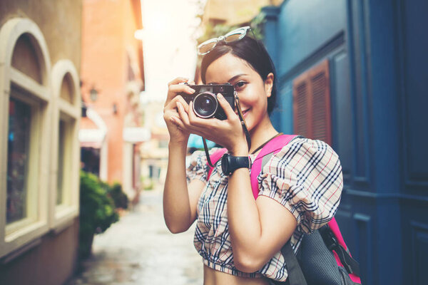 Close up of young hipster woman backpack traveling taking photo with her camera in urban.