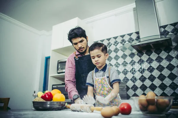 Dad teach his son how to cook in kitchen at home. Family concept.