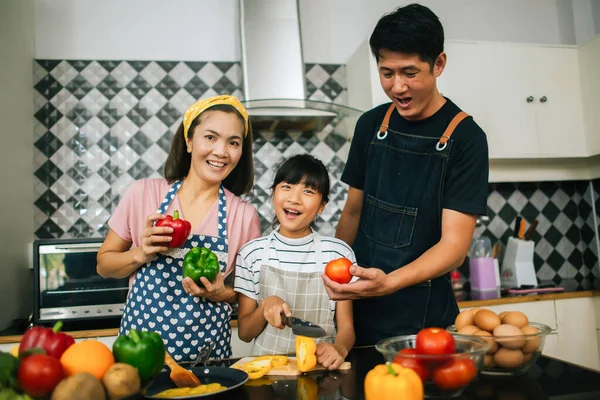 귀여운 소녀는 부엌에서 요리하면서 부모가 야채를 자르고 미소짓도록 — 스톡 사진