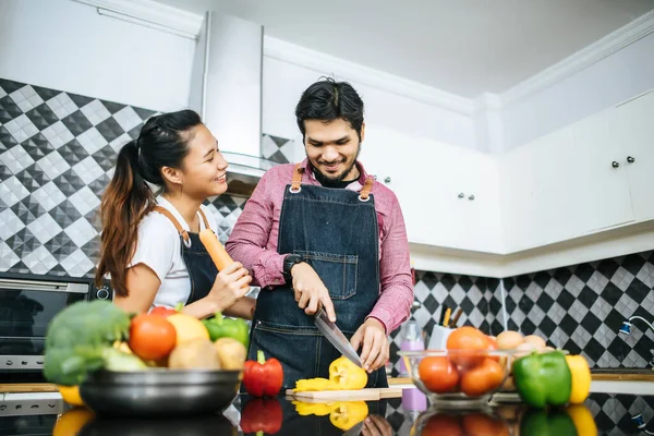 Happy young couple help each other chopping vegetable preparing for cooking in kitchen at home.