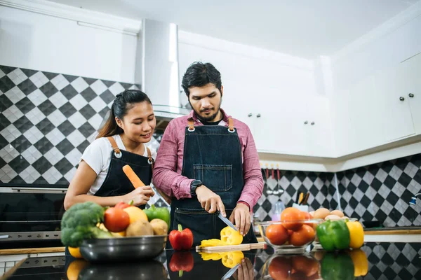 Happy young couple help each other chopping vegetable preparing for cooking in kitchen at home.