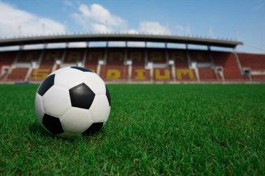 Stadyum arka planında çimlerin üzerinde futbol topu