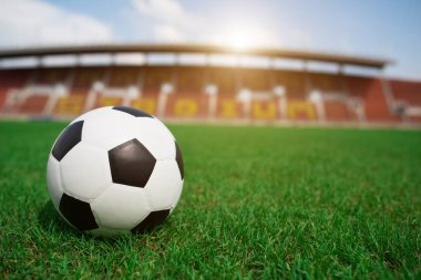 Stadyum arka planında çimlerin üzerinde futbol topu