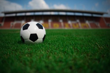 Stadyum arka planında çimlerin üzerinde futbol topu