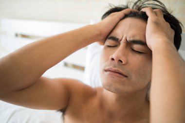 Endişeli bir adam sabahları yatakta oturuyor, ciddi bir şeyler düşünüyor.