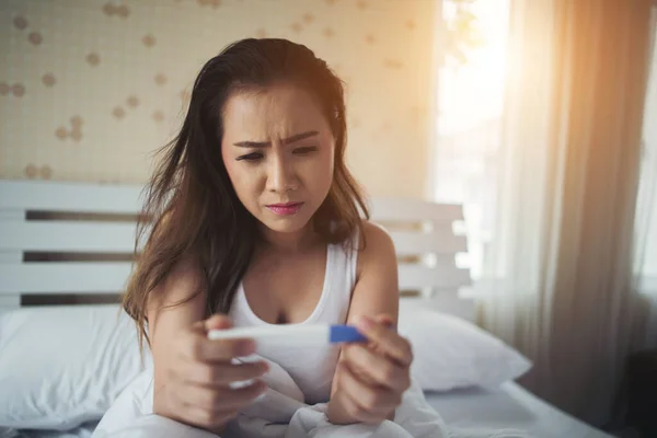 Λυπημένη Γυναίκα Διαμαρτύρεται Κρατώντας Ένα Τεστ Εγκυμοσύνης Κάθεται Στο Κρεβάτι — Φωτογραφία Αρχείου