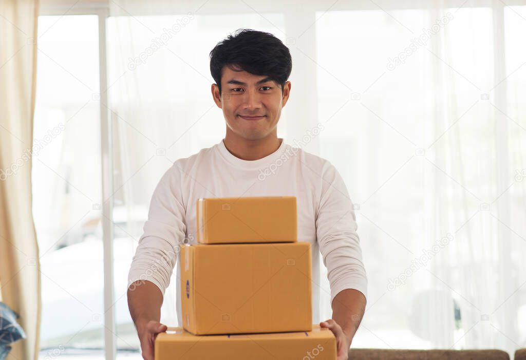 Young smiling logistic delivery man holding the box 