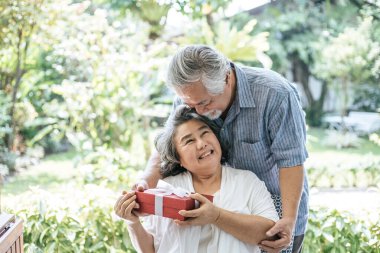 Gülümseyen koca, karısına sürpriz bir hediye kutusu veriyor.