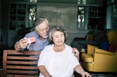 Gülümseyen koca, karısına sürpriz bir hediye kutusu veriyor.
