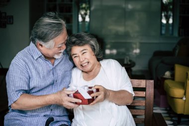 Gülümseyen koca, karısına sürpriz bir hediye kutusu veriyor.
