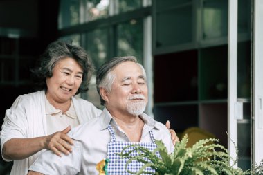 Yaşlı çiftler birlikte konuşuyor ve saksılara ağaç dikiyorlar..