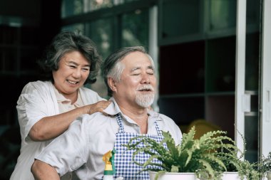 Yaşlı çiftler birlikte konuşuyor ve saksılara ağaç dikiyorlar..