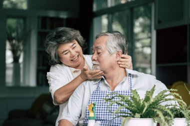 Yaşlı çiftler birlikte konuşuyor ve saksılara ağaç dikiyorlar..