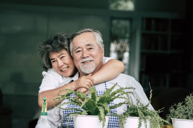 Yaşlı çiftler birlikte konuşuyor ve saksılara ağaç dikiyorlar..