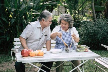 Yaşlı çiftler birlikte sağlıklı yemekler pişiriyor.