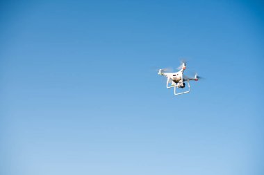 Beyaz İHA gökyüzünde bir video kaydediyor.