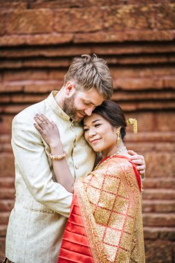 Asyalı gelin ve beyaz damat Tayland elbisesiyle romantik vakit geçiriyorlar.