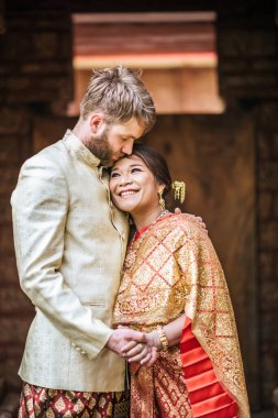 Asyalı gelin ve beyaz damat Tayland elbisesiyle romantik vakit geçiriyorlar.