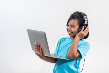 Dizüstü bilgisayar ve dinleme dersleri kullanan küçük bir kız. 