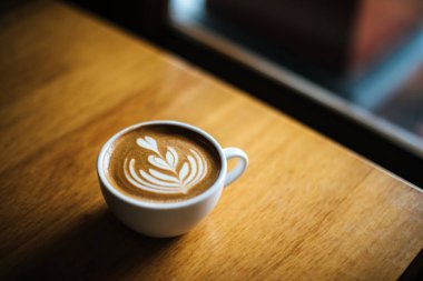 Kafe masasında kahve fincanındaki Latte sanatı.