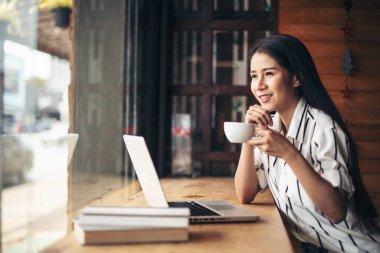 Kafede dizüstü bilgisayarla çalışan güzel bir kadın.