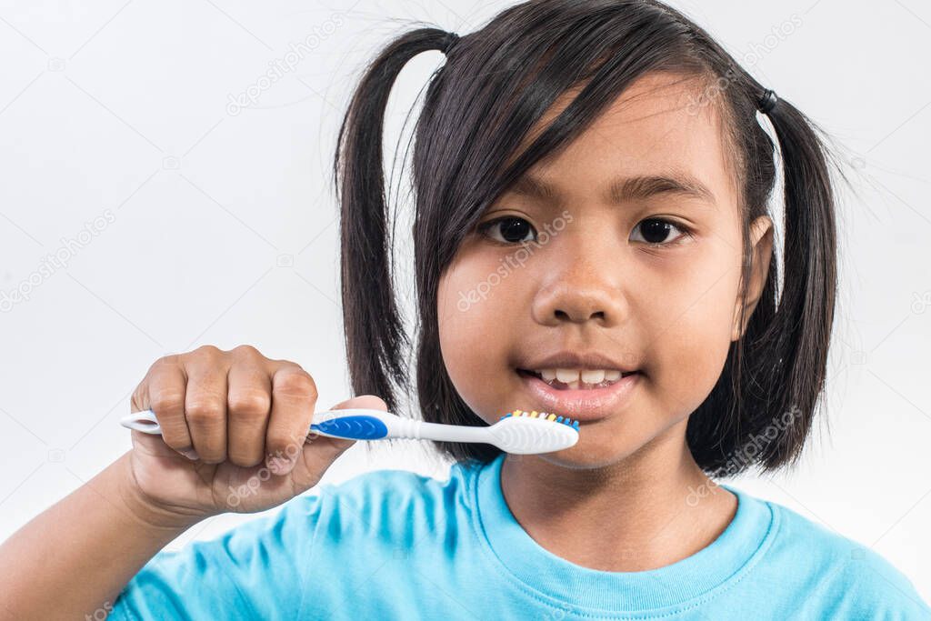 little girl brushing her teeth in studio shot