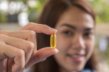 Kadın elinde haplarla doktorun tavsiyesine göre ilaç alıyor.