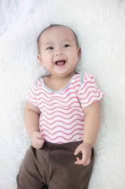 Mutlu bebek beyaz yatakta yatıyor.