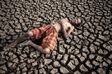 Yaşlı adamlar, elleri kuru ve çatlamış toprağa, küresel ısınmaya değmiş bir şekilde yere uzandılar.