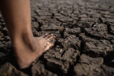 Çocuklar çamurda yalın ayak yürüyor, seçici bir odak noktası.