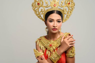 Taylandlı güzel bir kadın Tayland elbisesi giyiyor ve ayakta kendine sarılıyor.