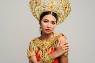 Taylandlı güzel bir kadın Tayland elbisesi giyiyor ve ayakta kendine sarılıyor.