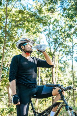 Dağ bisikletçileri dağın tepesinde durur ve bir şişe su içerler..