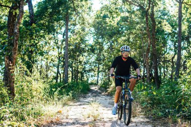 Dağ yolunda bisiklet süren adam.