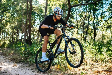 Dağ bisikletçileri bisikletlerde oturuyor.