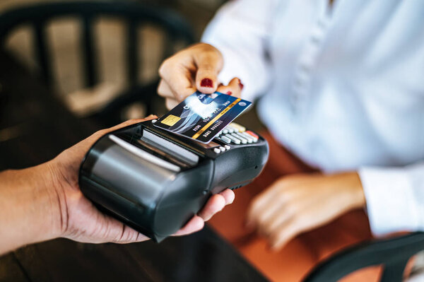 Close-up image of woman paying with credit card in cafe