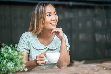 Genç bayan kahvede mutlu bir şekilde kahve içiyor..