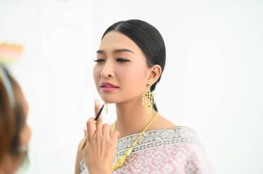 Tayland kostümü giyen kız makyaj yapıyor.