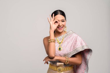 Tayland kıyafetleri giyen ve el işareti yapan kadınlar.