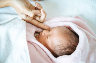 Yeni doğmuş bir bebeğin yüzüne dokunan annenin parmağı.