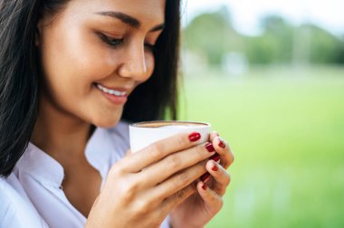 O kadın çayırda kahve içerek mutlu bir şekilde durdu..