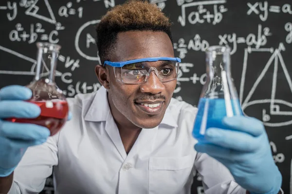 Scientists look at the sky blue chemicals in glass at the laboratory.